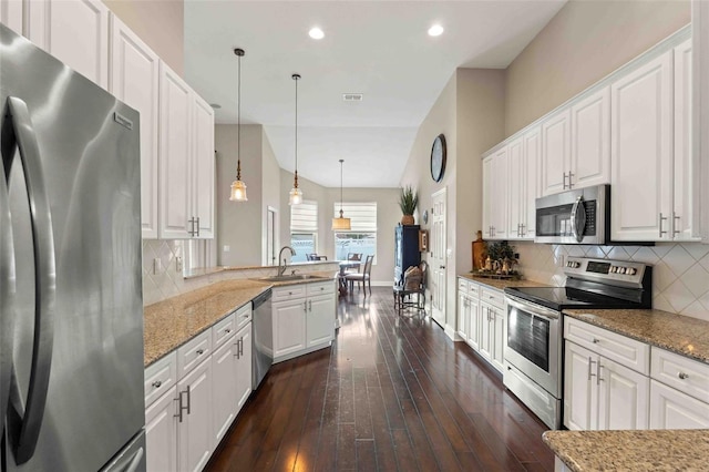 kitchen featuring kitchen peninsula, white cabinetry, pendant lighting, and stainless steel appliances