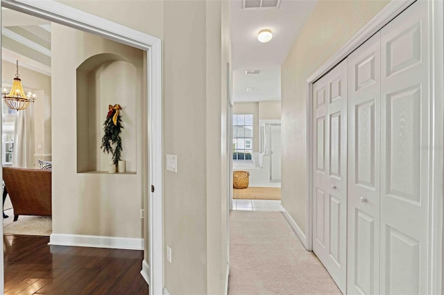 corridor with light hardwood / wood-style floors and an inviting chandelier