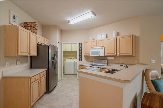 kitchen with kitchen peninsula, white appliances, sink, light brown cabinets, and washing machine and clothes dryer