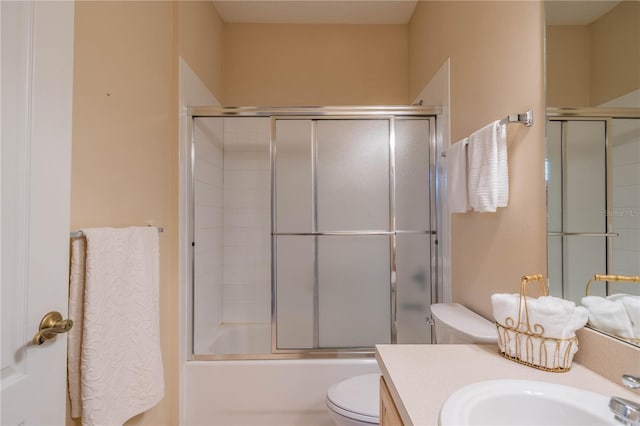 full bathroom with vanity, bath / shower combo with glass door, and toilet