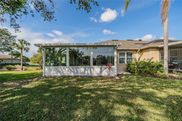 back of property with a lawn and a sunroom