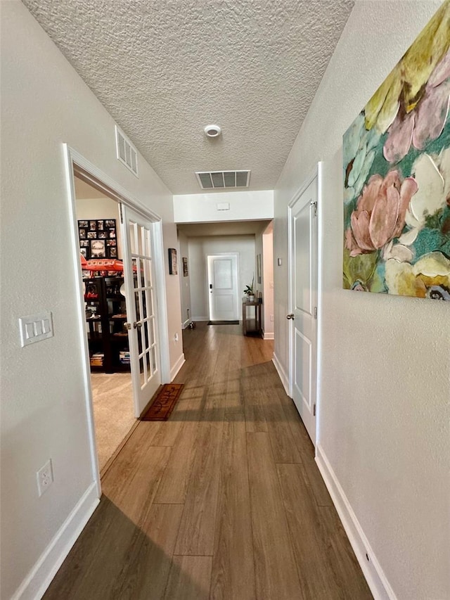 corridor with a textured ceiling, french doors, and dark hardwood / wood-style floors