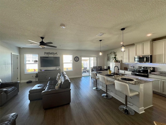 kitchen featuring a healthy amount of sunlight, stainless steel appliances, a kitchen breakfast bar, dark stone countertops, and pendant lighting