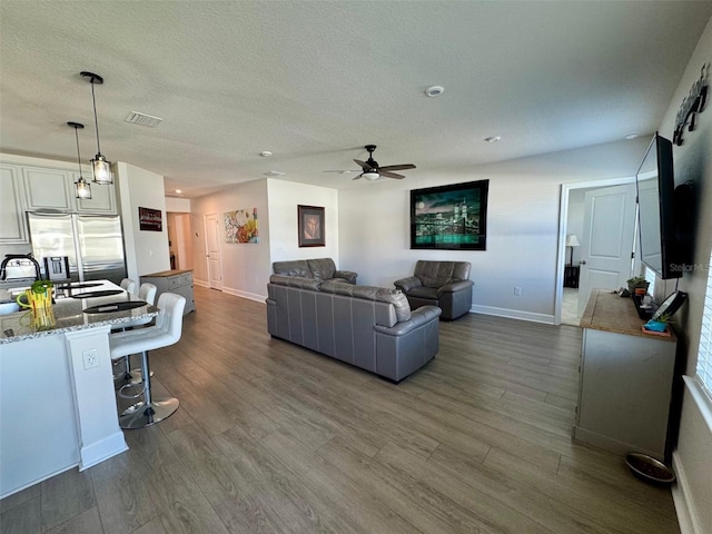 living room featuring a textured ceiling, ceiling fan, and dark wood-type flooring