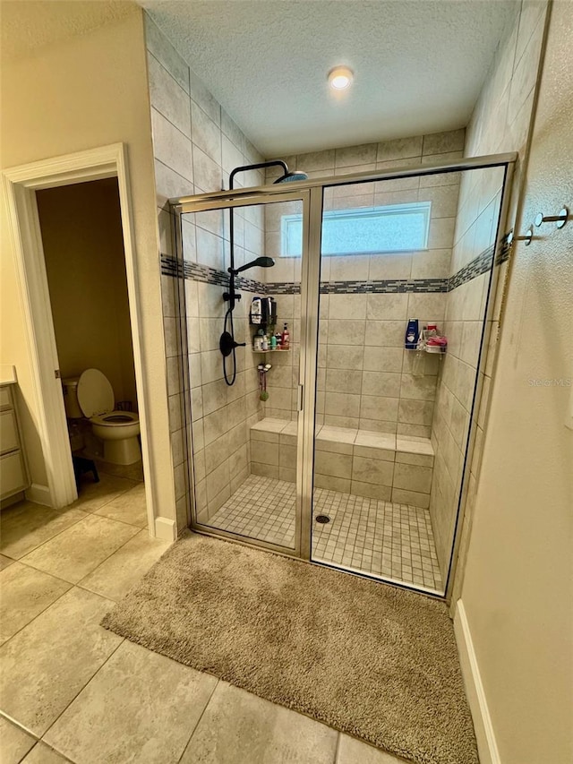 bathroom featuring toilet, a shower with door, and a textured ceiling