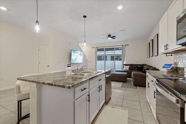 kitchen featuring a kitchen island with sink, sink, white cabinets, and hanging light fixtures