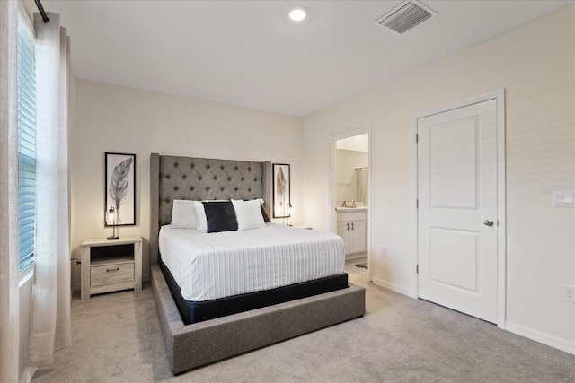 bedroom featuring light carpet and ensuite bath