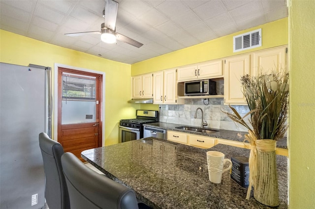 kitchen featuring dark stone counters, sink, ceiling fan, appliances with stainless steel finishes, and tasteful backsplash