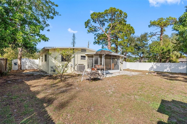 back of property with a sunroom, cooling unit, and a lawn