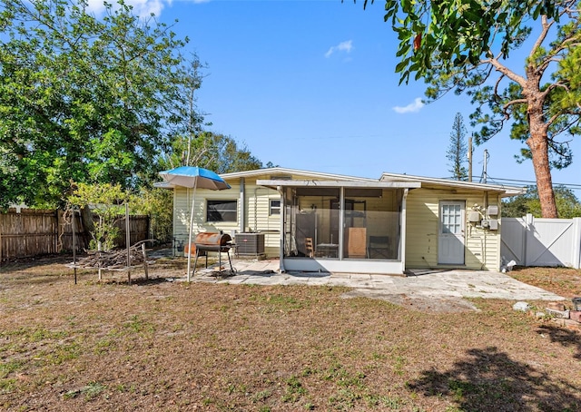 back of house with a patio, a sunroom, central AC unit, and a lawn