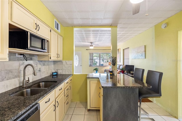 kitchen featuring dark stone counters, a breakfast bar, and sink