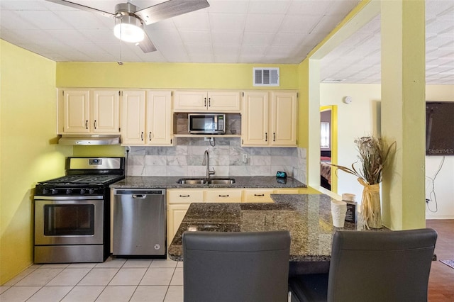 kitchen with tasteful backsplash, sink, dark stone countertops, kitchen peninsula, and stainless steel appliances