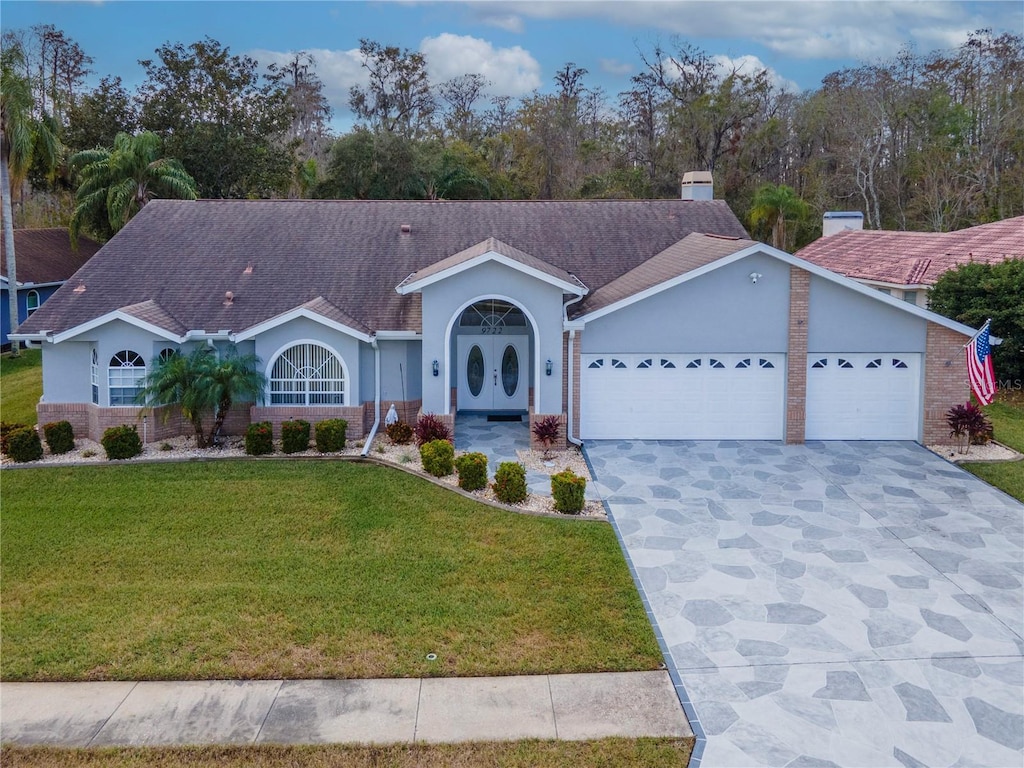 single story home featuring french doors, a front yard, and a garage