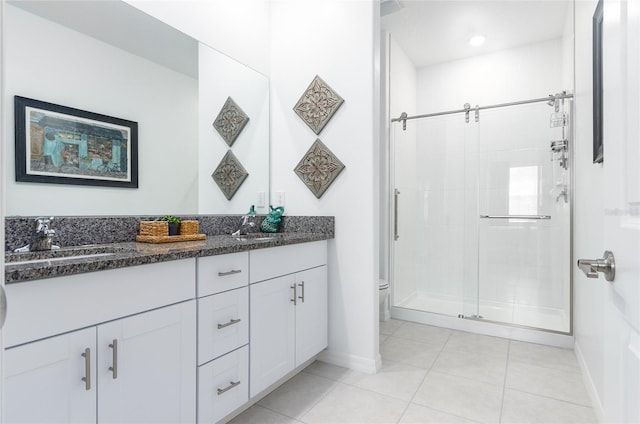 full bath featuring double vanity, toilet, a sink, a shower stall, and tile patterned flooring