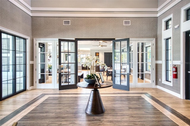 interior space with a towering ceiling, visible vents, wood finished floors, and french doors