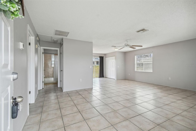 tiled spare room featuring ceiling fan, a healthy amount of sunlight, and a textured ceiling