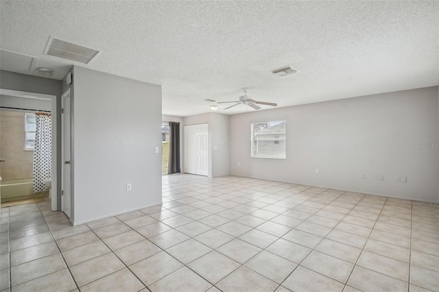 tiled empty room with ceiling fan and a textured ceiling