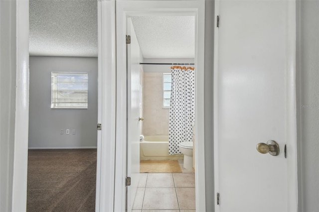 hallway with a textured ceiling, a healthy amount of sunlight, and light tile patterned flooring