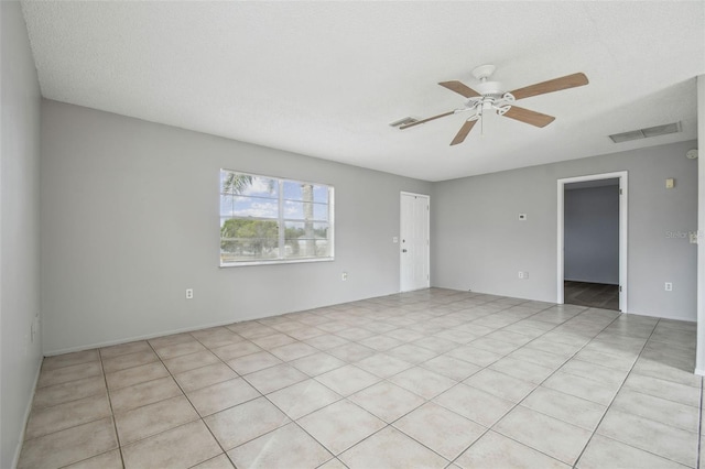 tiled empty room with ceiling fan and a textured ceiling