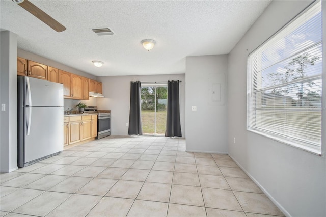 kitchen with ceiling fan, refrigerator, a textured ceiling, electric stove, and light tile patterned floors