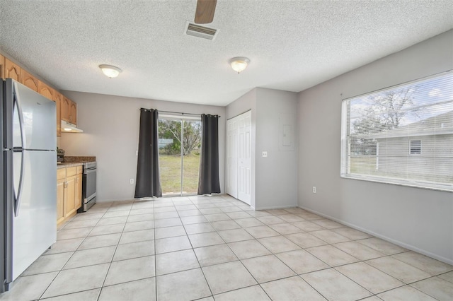 kitchen featuring light stone countertops, appliances with stainless steel finishes, a textured ceiling, and light tile patterned flooring