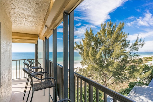 balcony featuring a view of the beach and a water view