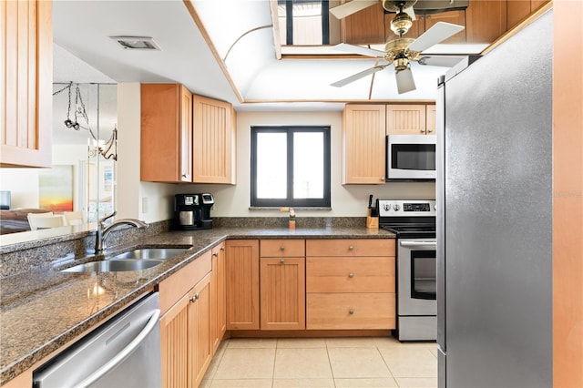 kitchen featuring ceiling fan, sink, stainless steel appliances, dark stone countertops, and light tile patterned floors