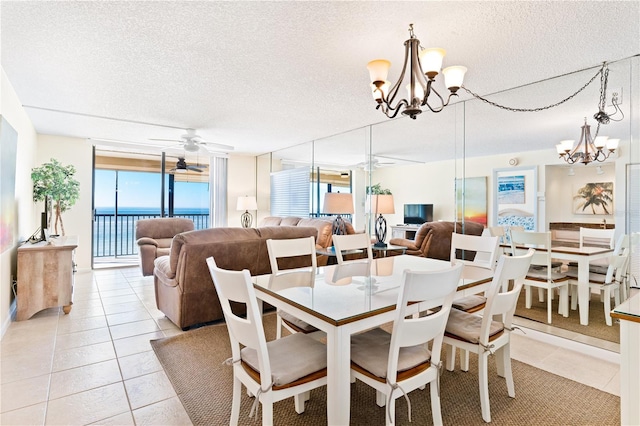 dining room featuring a wall of windows, light tile patterned flooring, a textured ceiling, a water view, and ceiling fan with notable chandelier