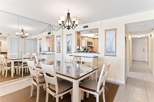 dining room with a textured ceiling, a notable chandelier, and light tile patterned flooring