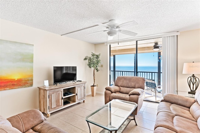 tiled living room with ceiling fan, a textured ceiling, and a wall of windows