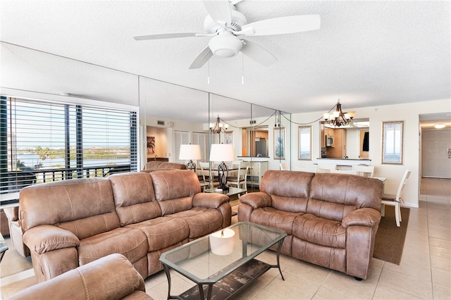 tiled living room with ceiling fan with notable chandelier and a textured ceiling