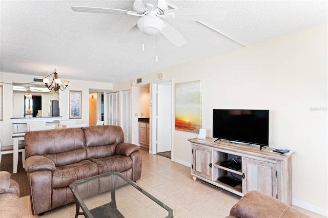 tiled living room with ceiling fan with notable chandelier and a textured ceiling