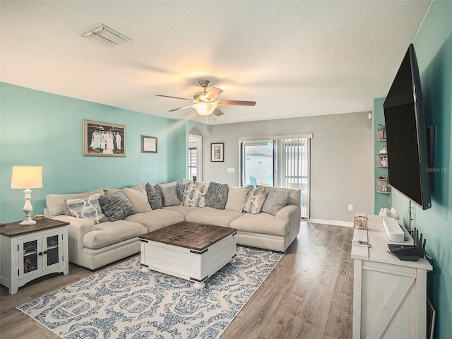 living room featuring ceiling fan, a textured ceiling, and hardwood / wood-style flooring