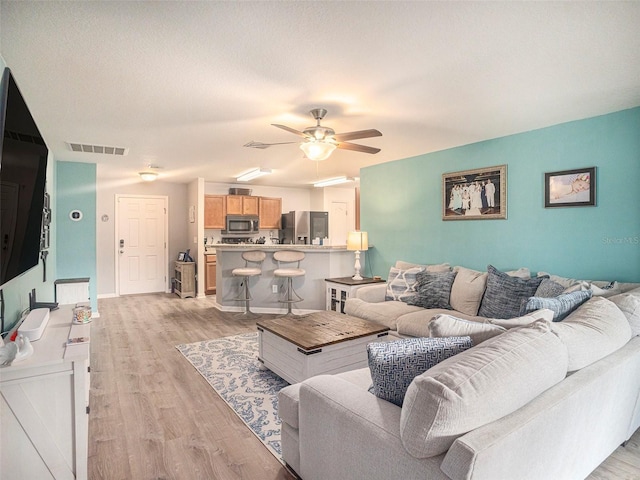 living room featuring light wood-type flooring and ceiling fan