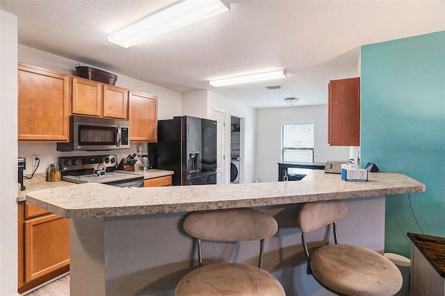 kitchen with a kitchen breakfast bar, kitchen peninsula, stainless steel appliances, and a textured ceiling