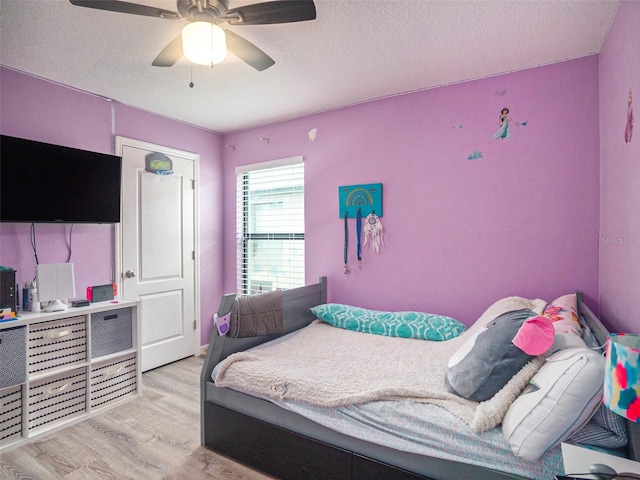 bedroom with ceiling fan, a textured ceiling, and light hardwood / wood-style flooring