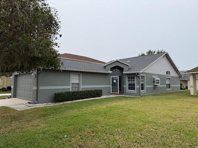 ranch-style home with a garage and a front lawn