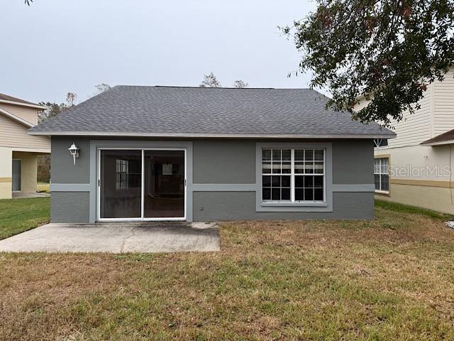 back of property with a lawn and a patio area