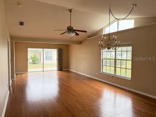 empty room with hardwood / wood-style flooring, ceiling fan with notable chandelier, and lofted ceiling