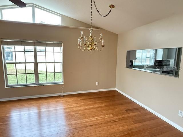 unfurnished dining area featuring hardwood / wood-style floors, a chandelier, and lofted ceiling