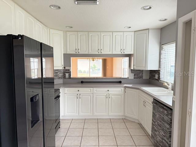 kitchen featuring stainless steel fridge, dishwashing machine, sink, white cabinets, and light tile patterned flooring