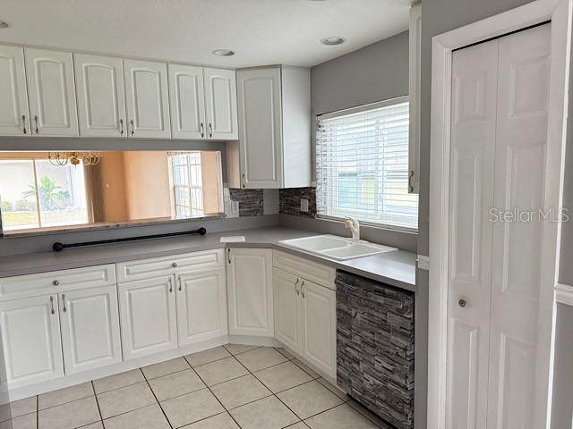 kitchen with white cabinets, light tile patterned floors, dishwasher, and sink