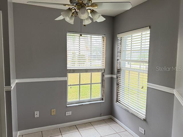 tiled empty room with ceiling fan and a healthy amount of sunlight