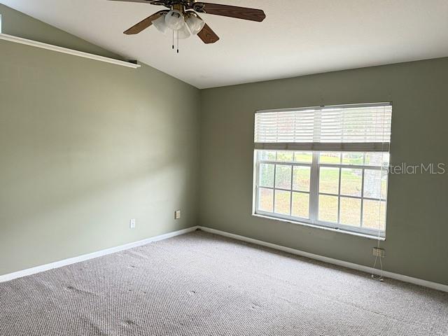 carpeted empty room featuring vaulted ceiling and ceiling fan