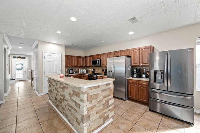 kitchen featuring decorative backsplash, light tile patterned flooring, stainless steel appliances, and a kitchen island with sink