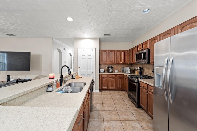 kitchen with sink, backsplash, appliances with stainless steel finishes, light tile patterned floors, and ornamental molding