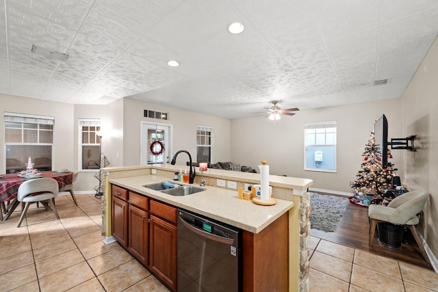 kitchen featuring ceiling fan, dishwasher, sink, a kitchen island with sink, and light tile patterned floors