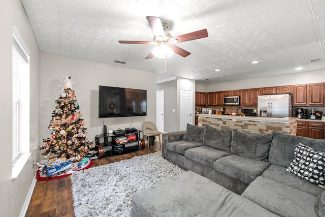 living room featuring a healthy amount of sunlight, ceiling fan, and dark wood-type flooring