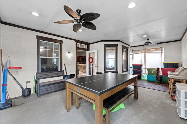 playroom featuring a textured ceiling, concrete floors, crown molding, and ceiling fan