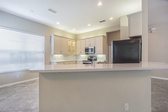 kitchen featuring light tile patterned floors, backsplash, stainless steel appliances, and a center island with sink